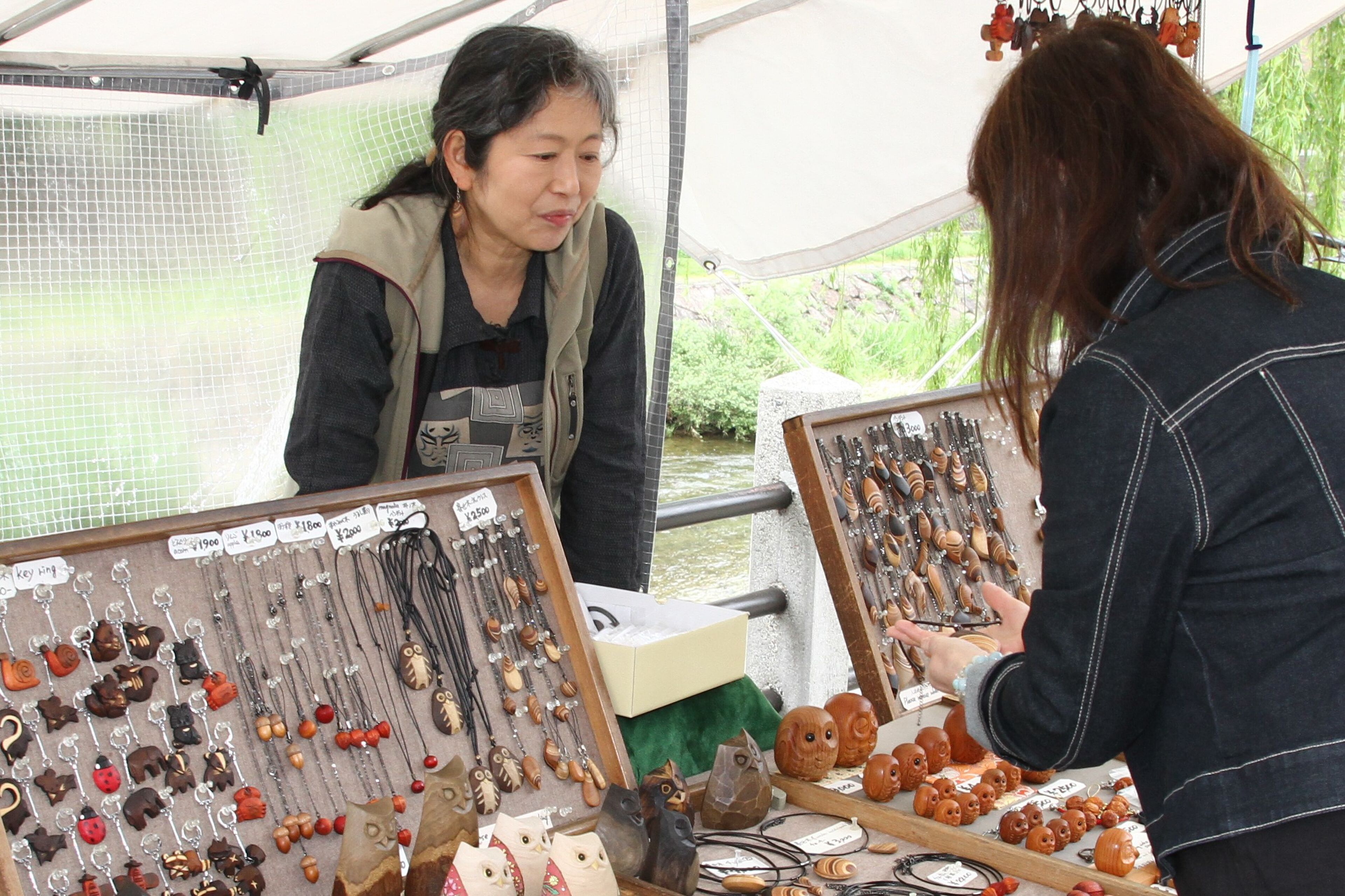 A market stall with various wooden crafts and keychains on display.