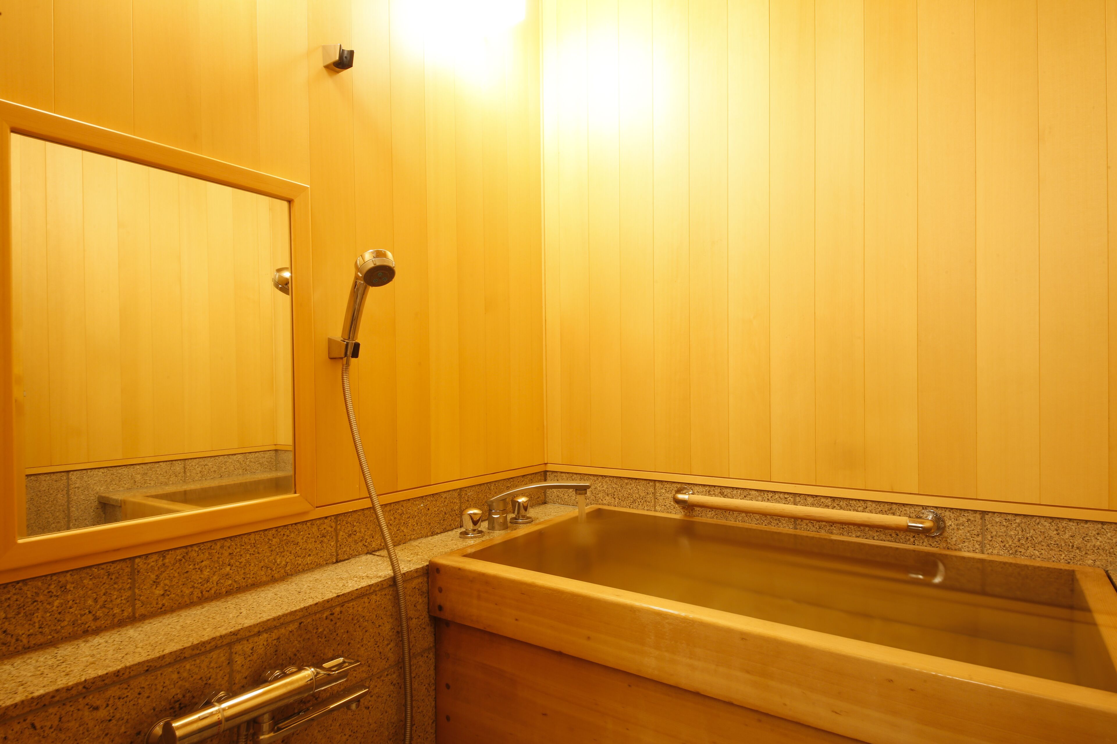 A wooden bathroom with a bathtub, a shower, and a mirror.