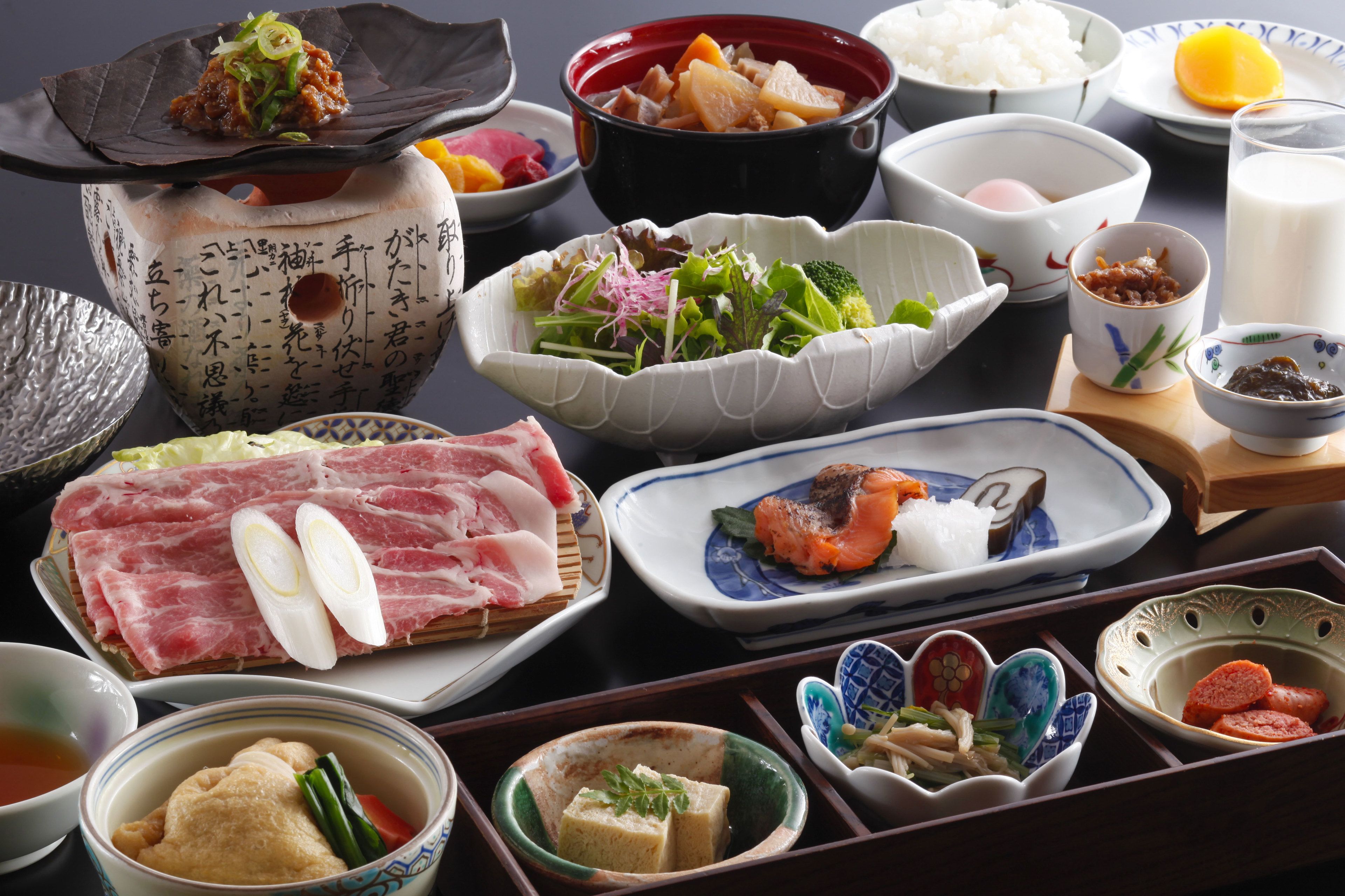 A variety of dishes and bowls on a table, including sushi, vegetables, and other Asian cuisine.