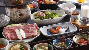 A variety of dishes and bowls on a table, including sushi, vegetables, and other Asian cuisine.