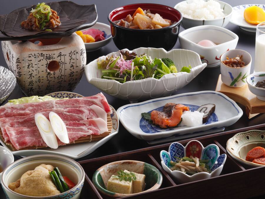 A variety of dishes and bowls on a table, including sushi, vegetables, and other Asian cuisine.