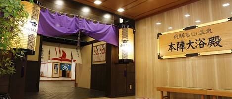 A traditional Japanese interior with tatami flooring, a wooden bench, and a sign with Japanese characters.