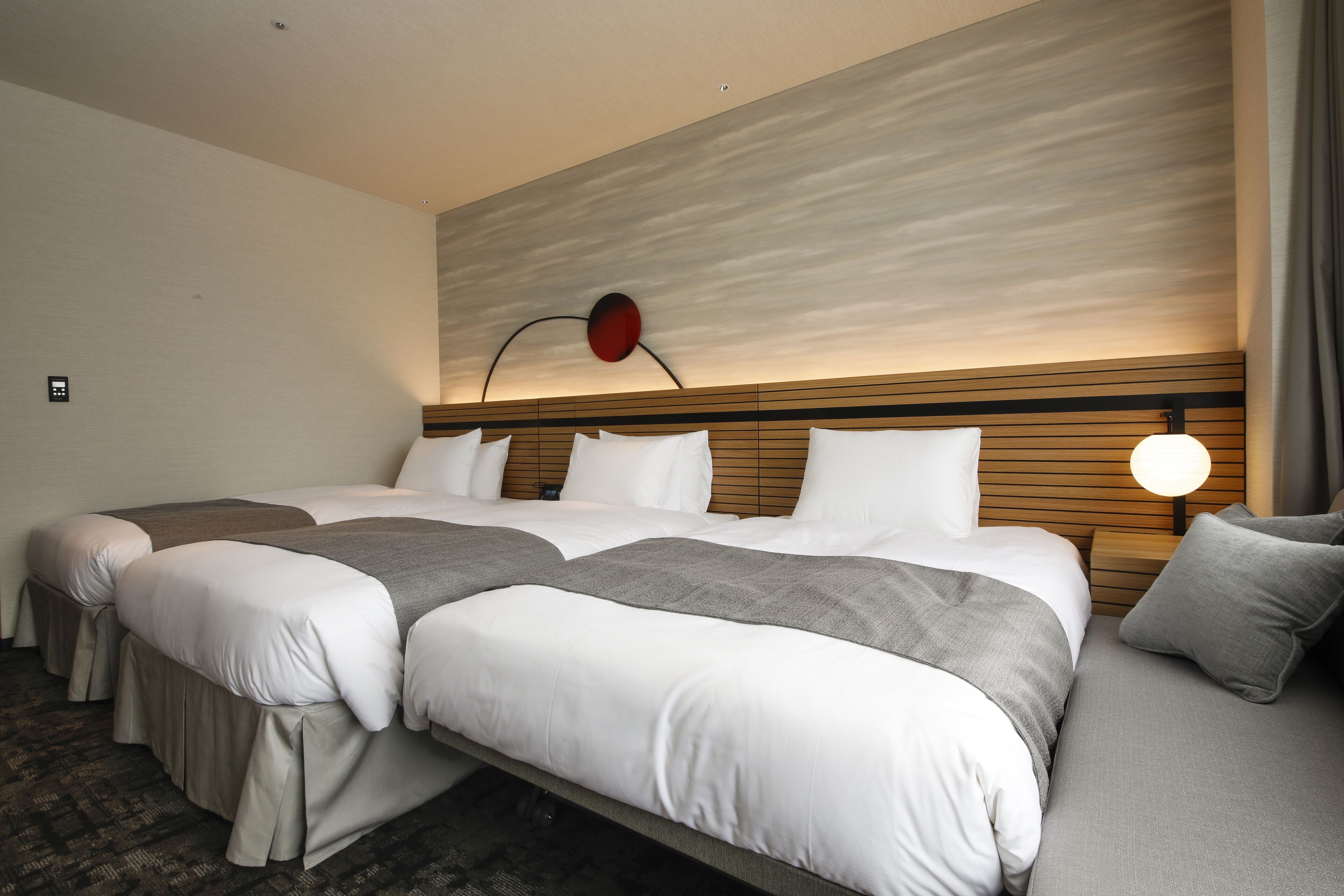 Quarto de hotel com cama grande, mesa de cabeceira, abajur e design moderno na parede.