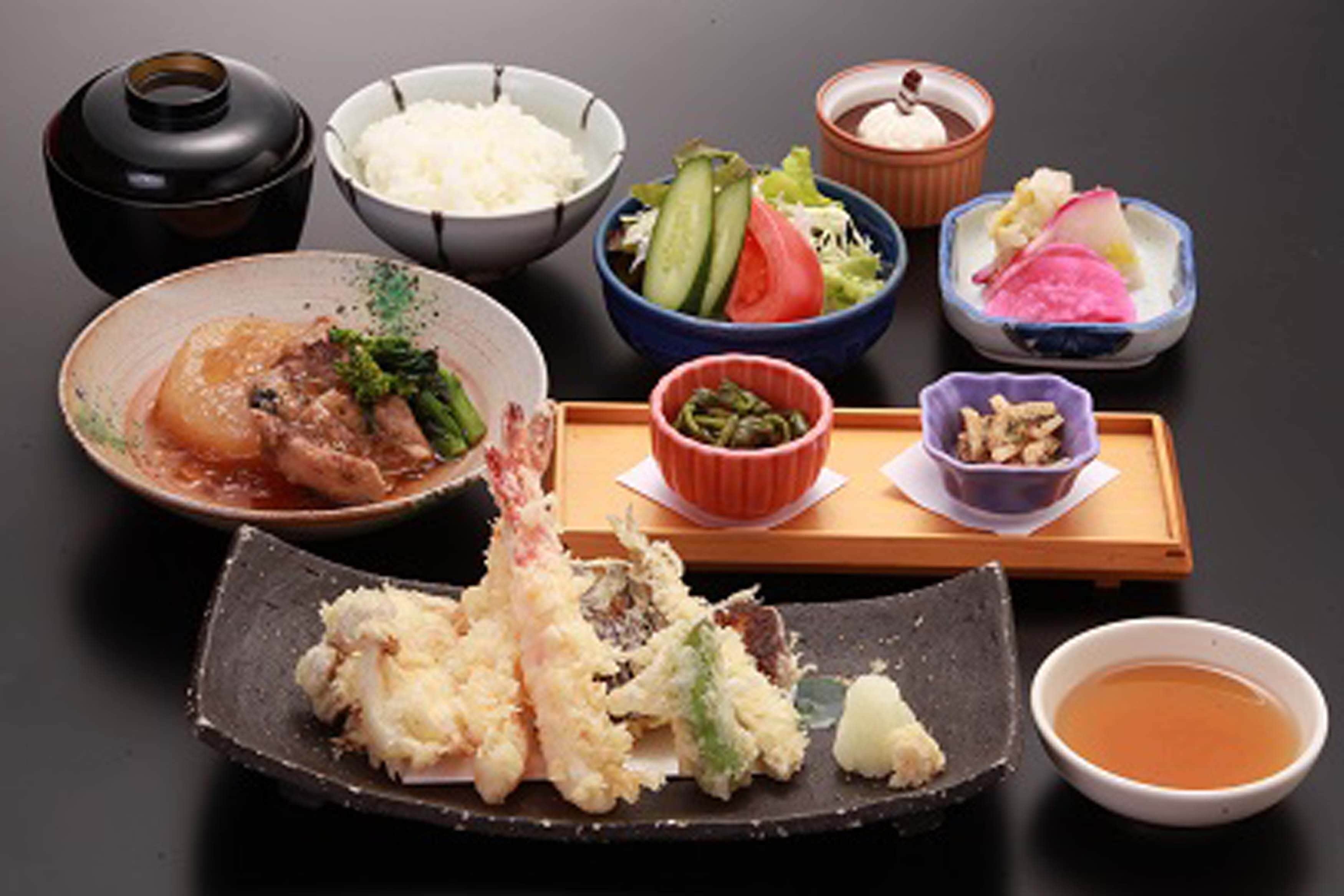 Una comida tradicional japonesa con diversos platos que incluyen arroz, sashimi y verduras.