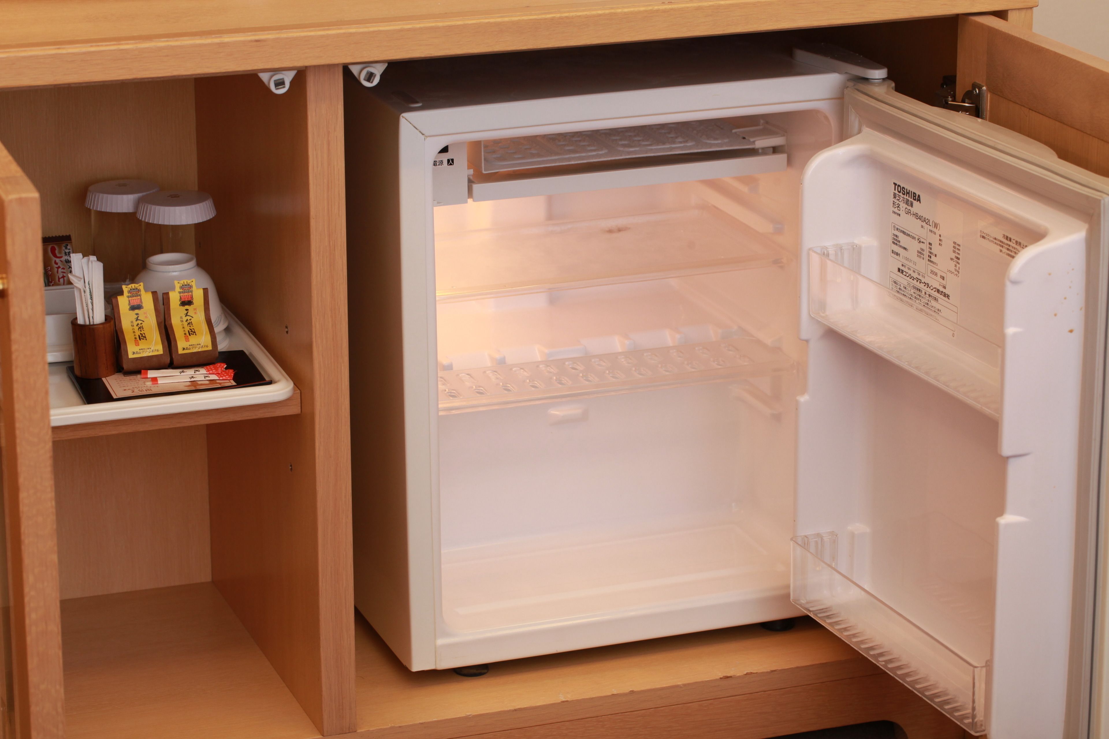 Un petit réfrigérateur doté d’une porte transparente, d’une étagère intégrée et d’un petit compartiment pour les condiments.