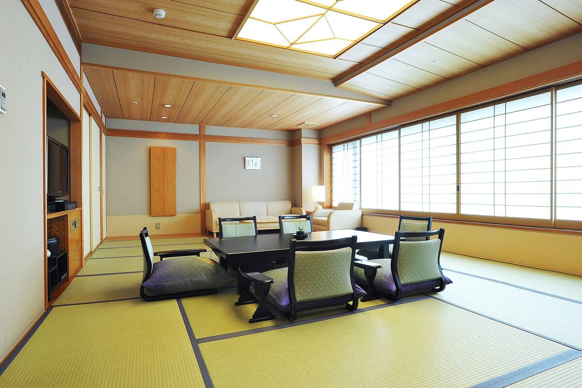 A traditional Japanese room with tatami flooring, a low table, and seating.