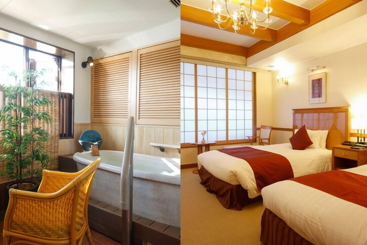 A room with a bathtub, a chair, a bed with a red blanket, and a wooden ceiling.