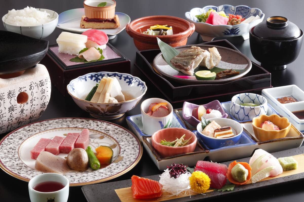 A variety of Japanese dishes arranged on a table, including sushi, sashimi, and other delicacies.