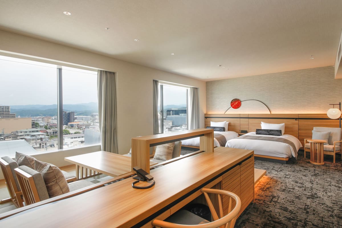 A modern hotel room with a large bed, a desk, and a view of the city.