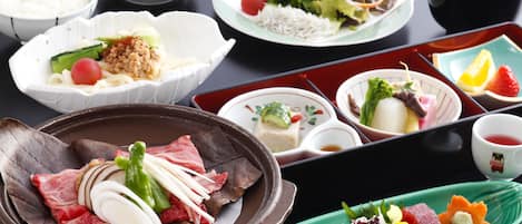 A variety of dishes including a bowl of rice, a plate with vegetables and meat, and a small dish with a green vegetable.