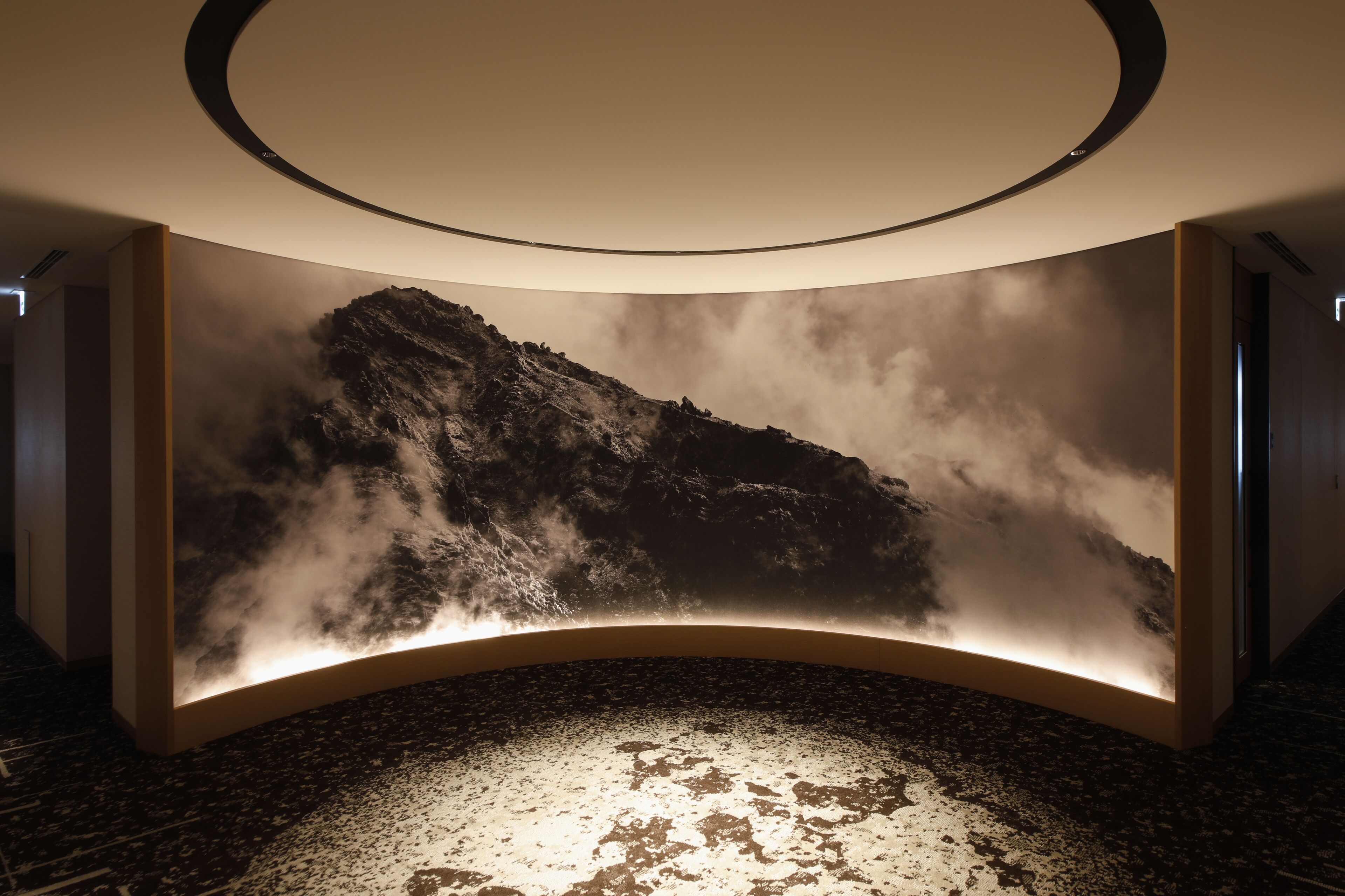 Un interior moderno con una gran pared iluminada que muestra un paisaje montañoso.