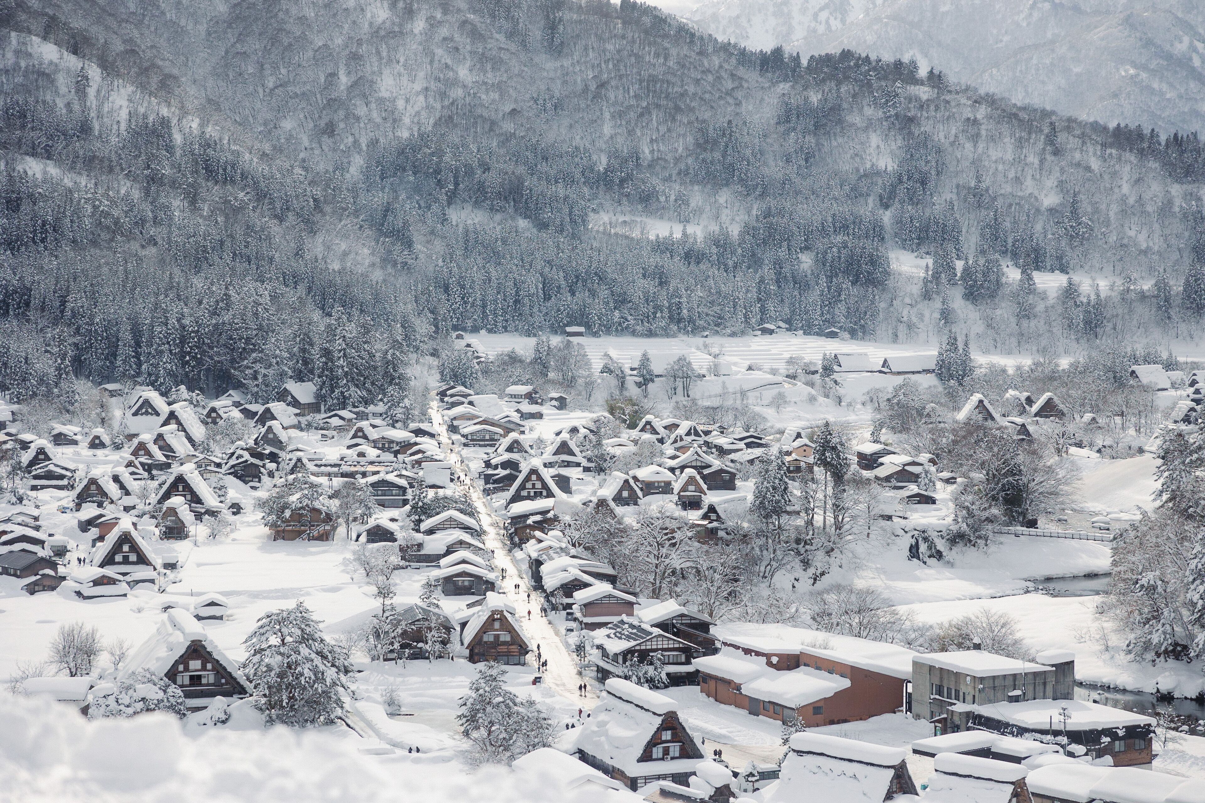 A snow-covered village with traditional wooden houses and a modern building.