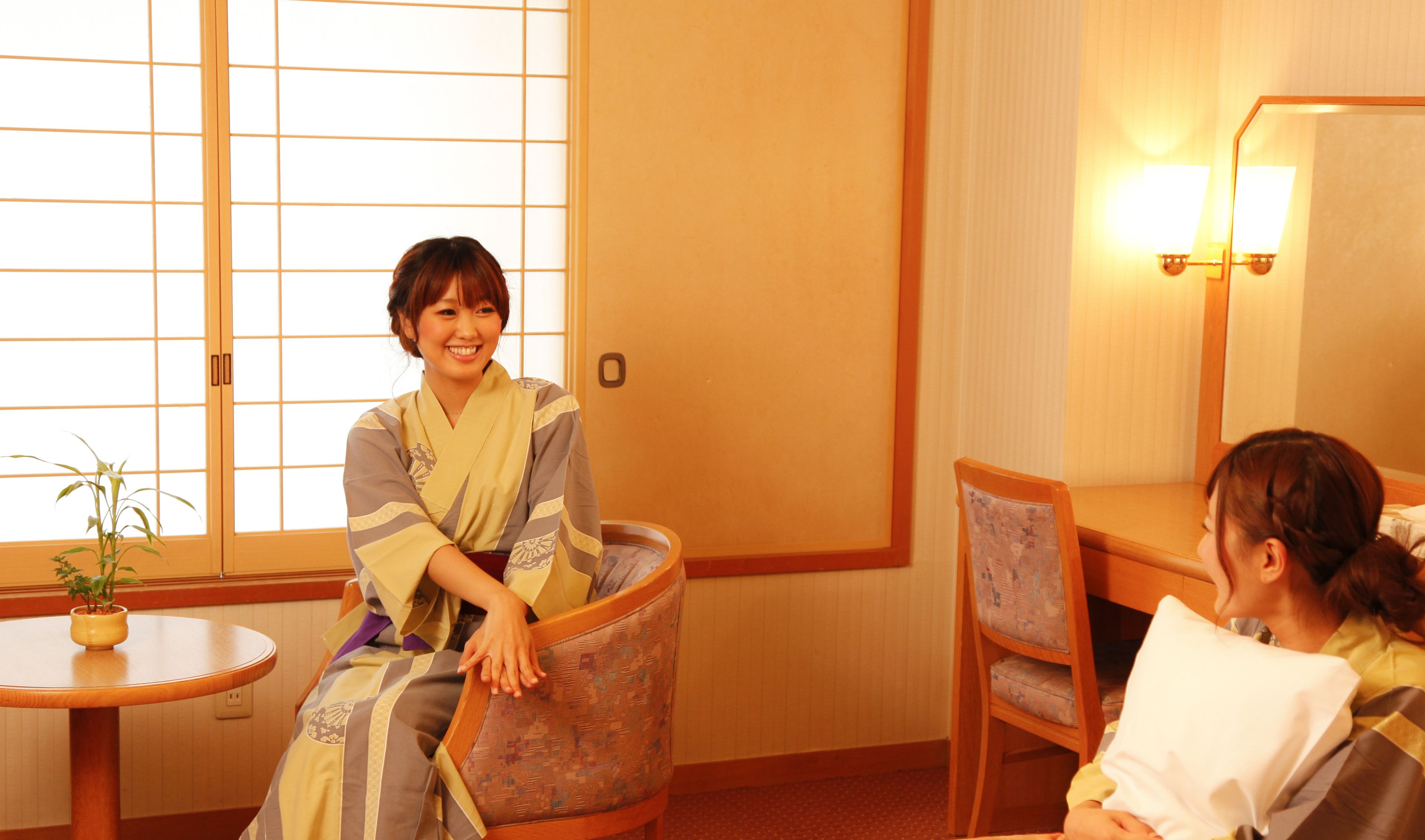 A traditional Japanese room with tatami flooring, a low wooden table with a potted plant, and a seating area with cushions.
