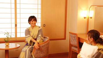 A traditional Japanese room with tatami flooring, a low wooden table with a potted plant, and a seating area with cushions.
