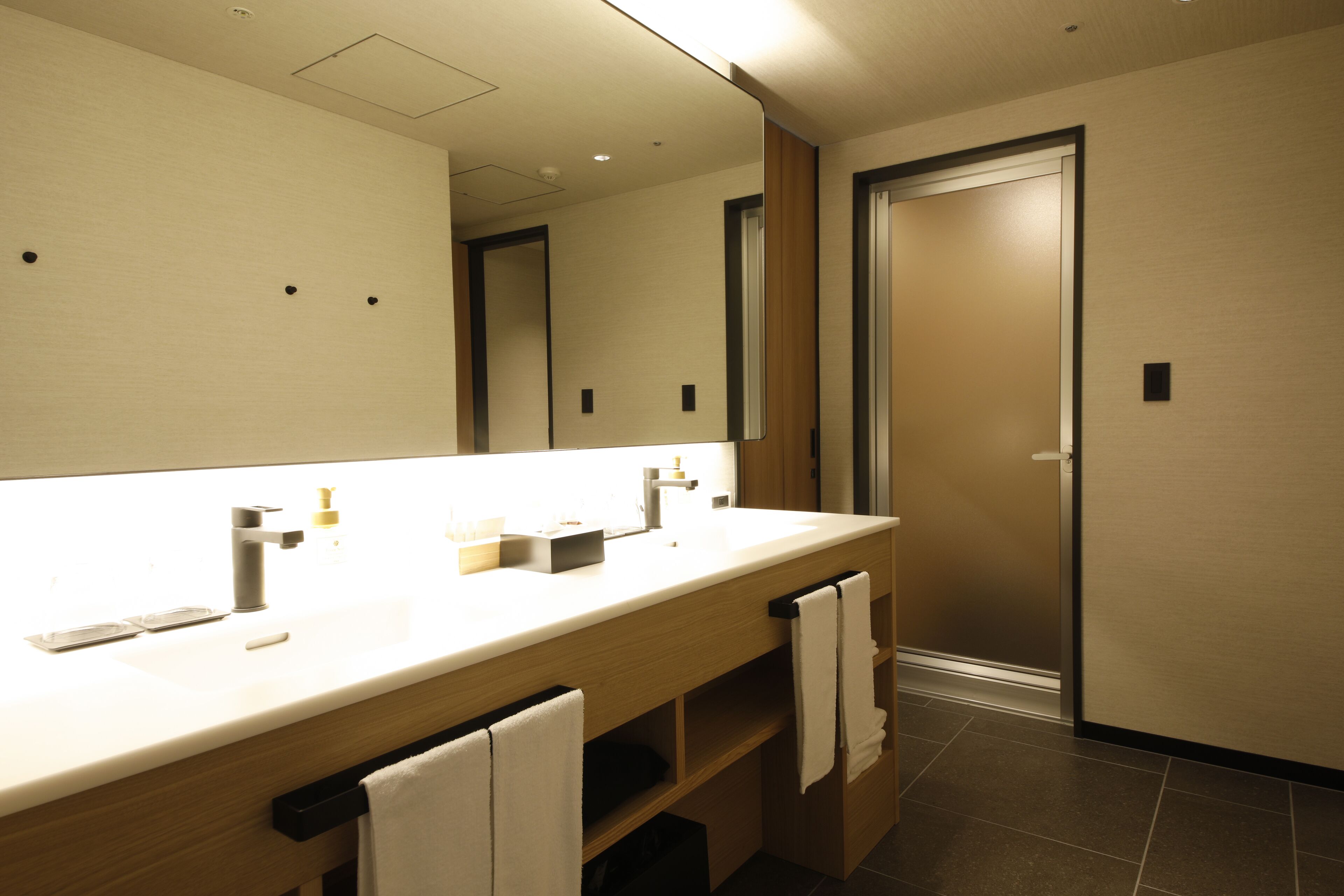 A modern bathroom with a large mirror, a sink, and a towel rack.