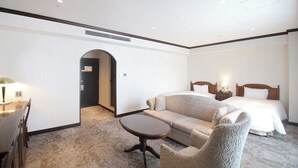 A hotel room with a bed, a sofa, a small table, and a desk with a lamp. - Hotel Piena Kobe (Kobe)