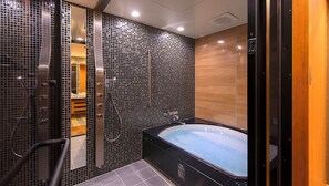 A modern bathroom with a black bathtub, a shower area, and a wooden vanity. - Hotel Piena Kobe (Kobe)