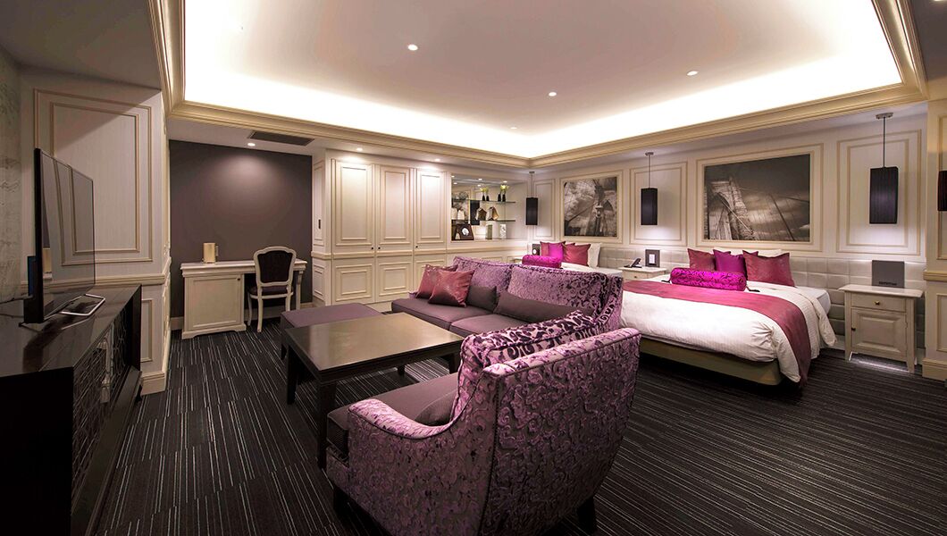 A hotel room with a large bed, a sofa, a desk, and a television.