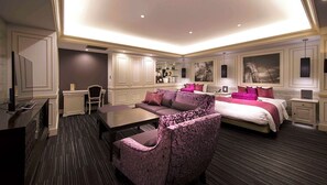 Een hotelkamer met een groot bed, een bank, een bureau en een televisie.