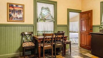 A dining area with a table and chairs, a window with curtains, and a door leading to another room.