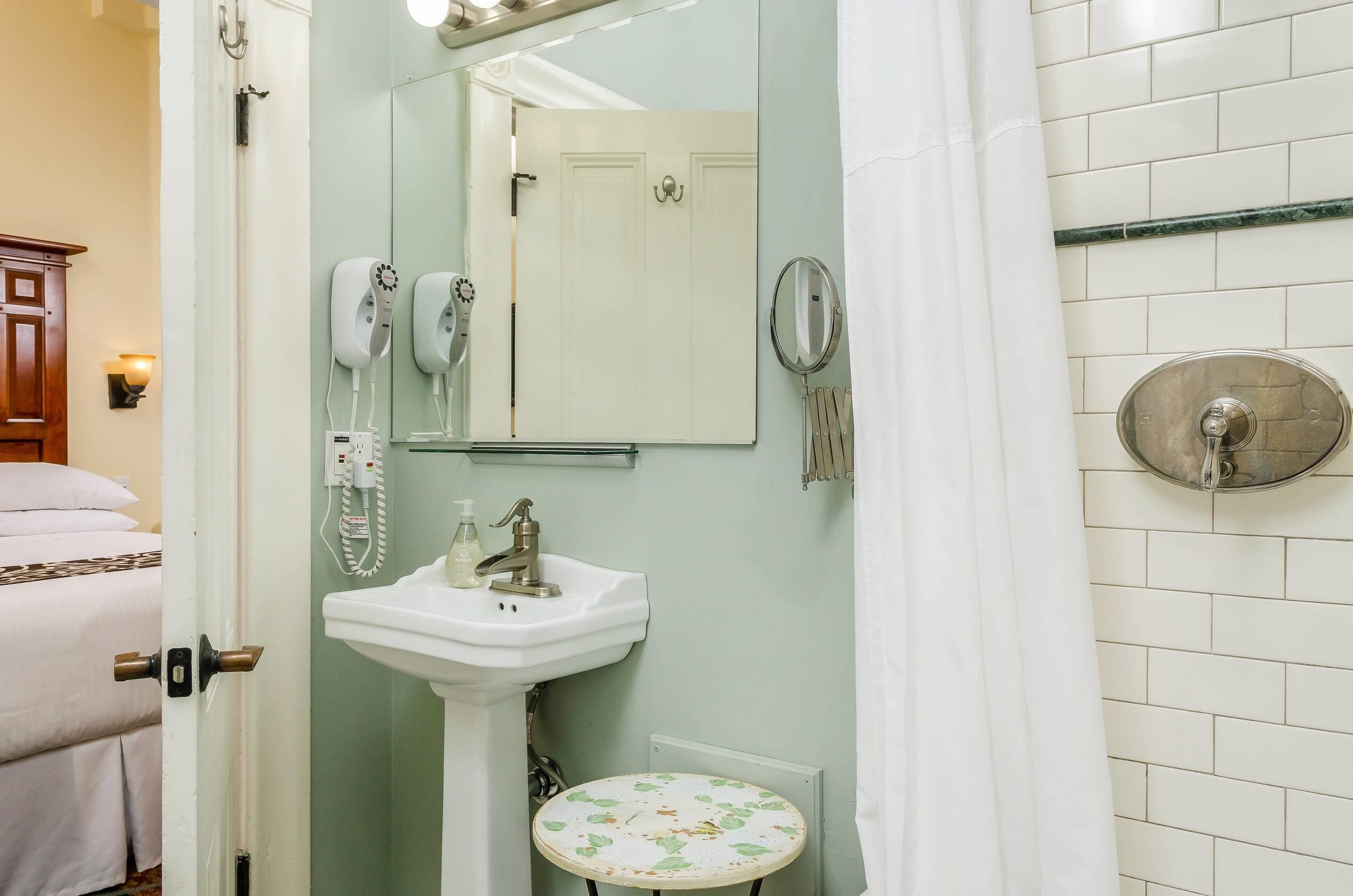 Un baño con lavamanos, espejo y zona de ducha.