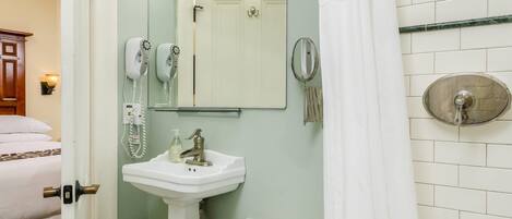 Un baño con lavamanos, espejo y zona de ducha.
