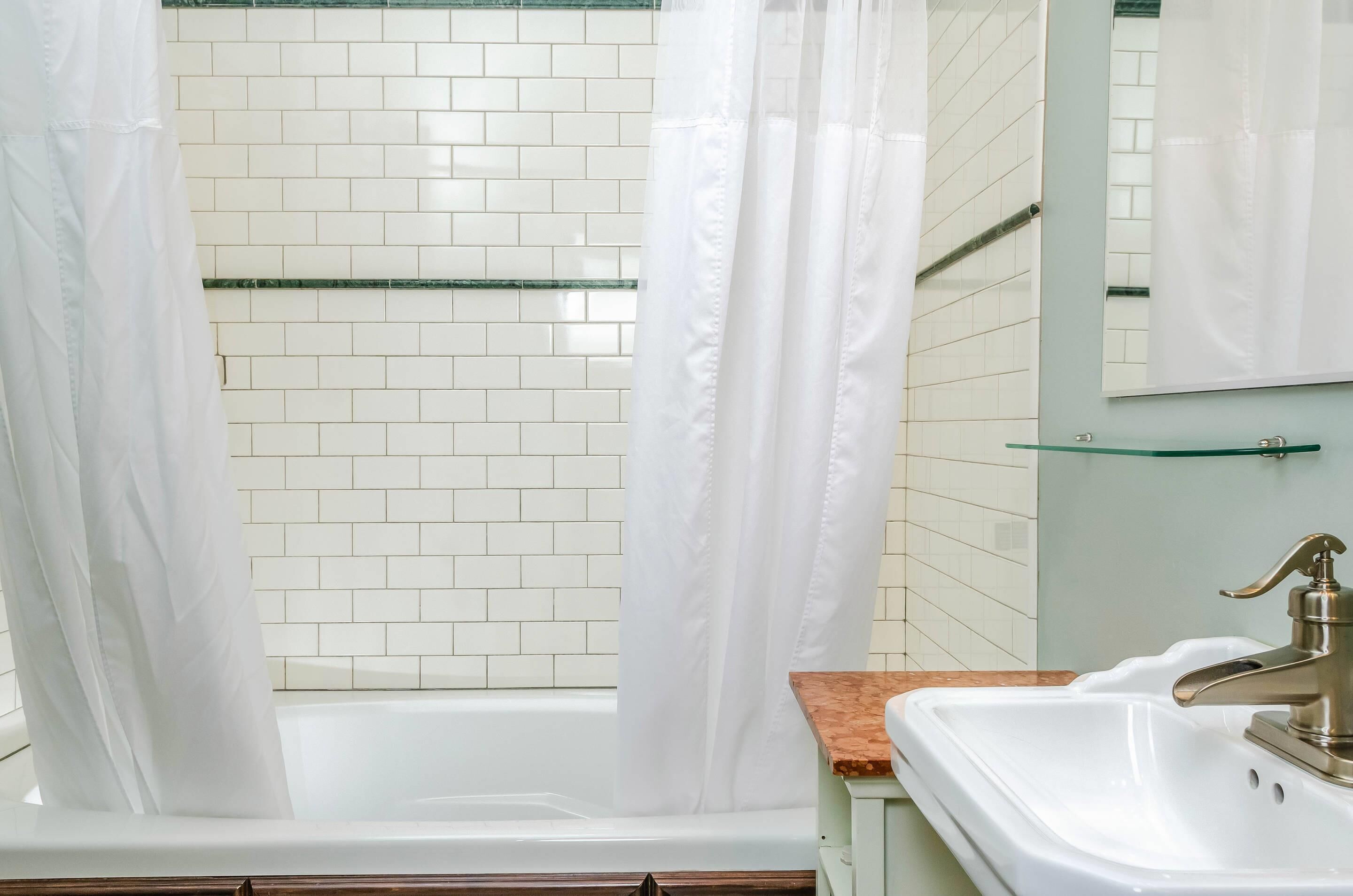 Un baño con una bañera blanca, cabina de ducha de cristal, lavabo con encimera de madera y espejo sobre el lavabo.