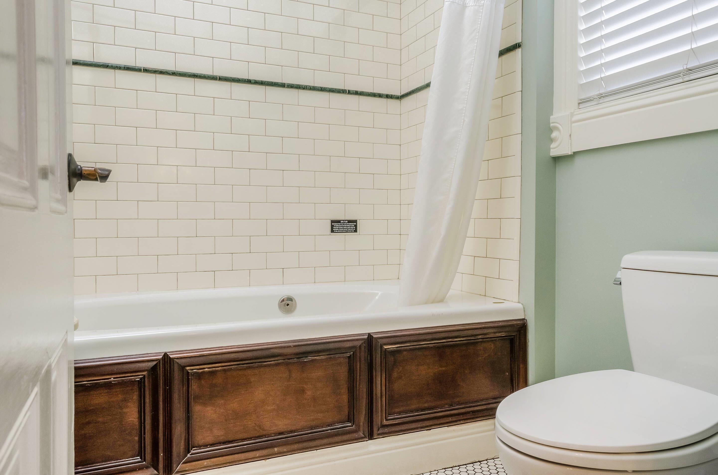 A bathroom with a white bathtub, a white toilet, and a shower curtain.