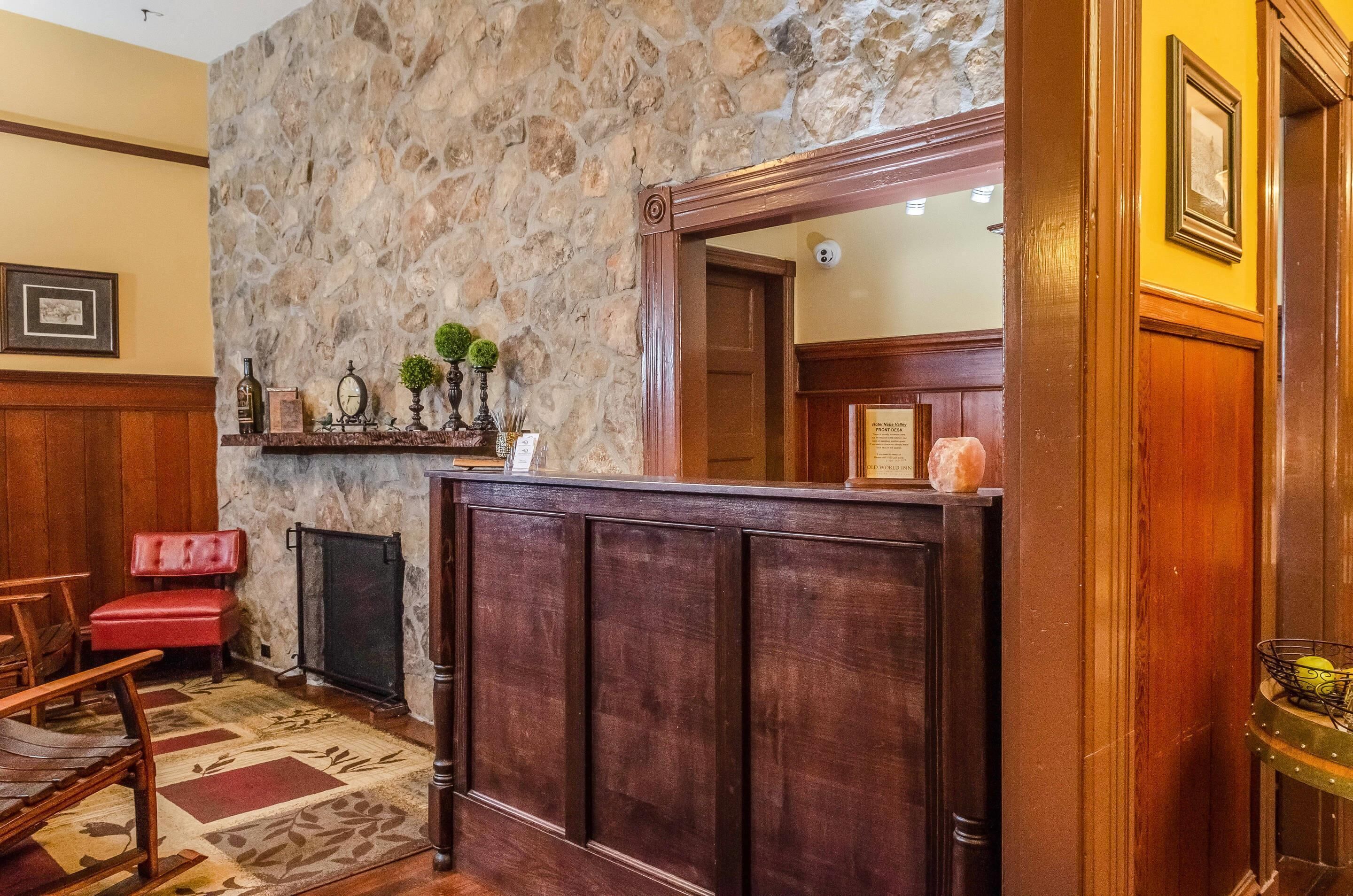 A reception area with a stone wall, wooden paneling, a red leather bench, and a framed mirror.