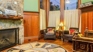 A cozy living room with a stone fireplace, two leather armchairs, a wooden coffee table, and a large window with curtains. - Hotel Napa Valley, an Ascend Collection Hotel (Napa)