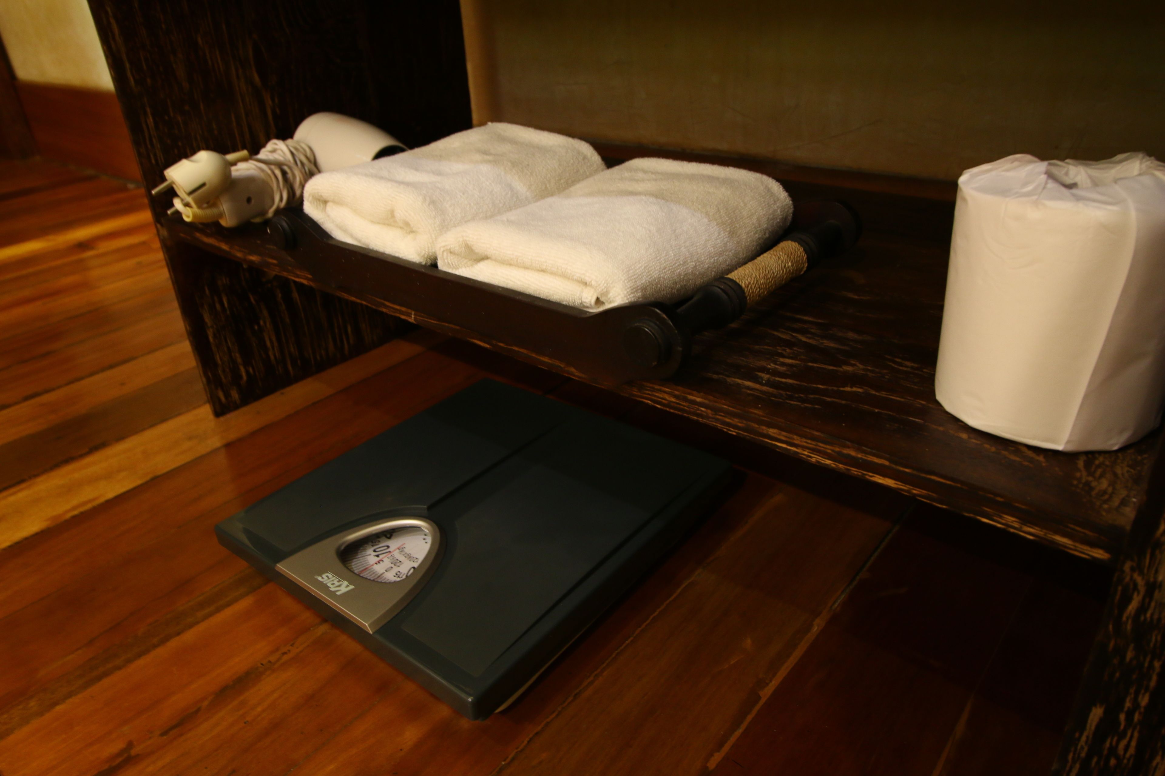 A wooden bench with towels and a scale.