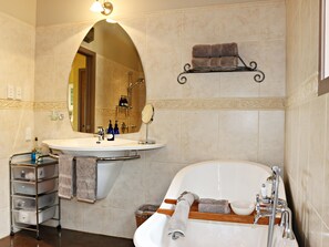 A bathroom with a sink, mirror, towel rack, and bathtub. - Huntington Stables Retreat Accommodation (Cambridge)