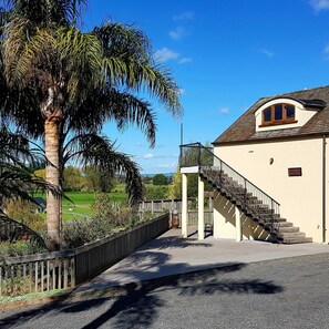 A building with a staircase leading to a balcony, surrounded by a fence and a palm tree. - Huntington Stables Retreat Accommodation (Cambridge)