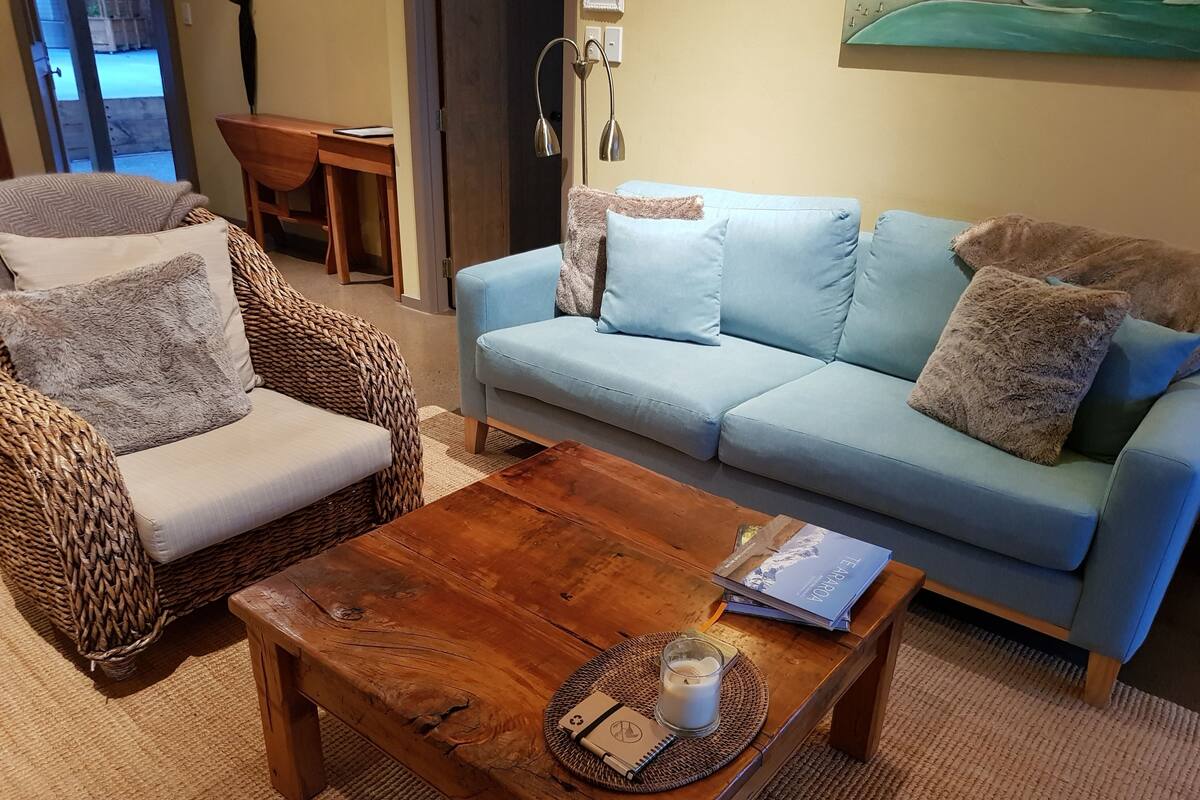 A cozy living room with a wicker armchair, a light blue sofa, and a wooden coffee table.