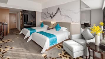A hotel room with two beds, a sofa, a desk, and a chair.