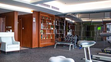 A gym with exercise equipment, a reception desk, and wooden shelving with plants.