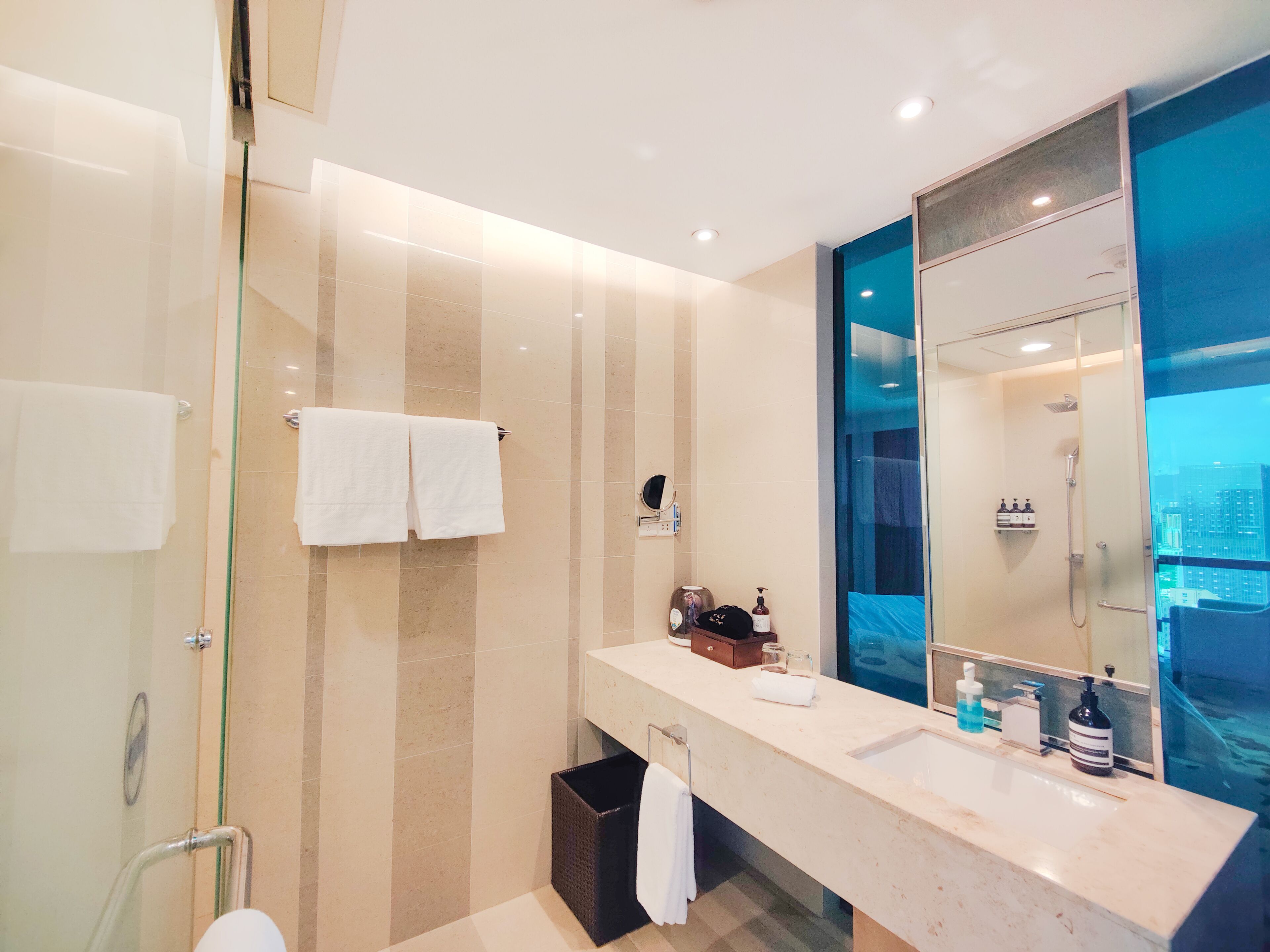 A modern bathroom with a glass shower enclosure, a large mirror, and a vanity with toiletries.