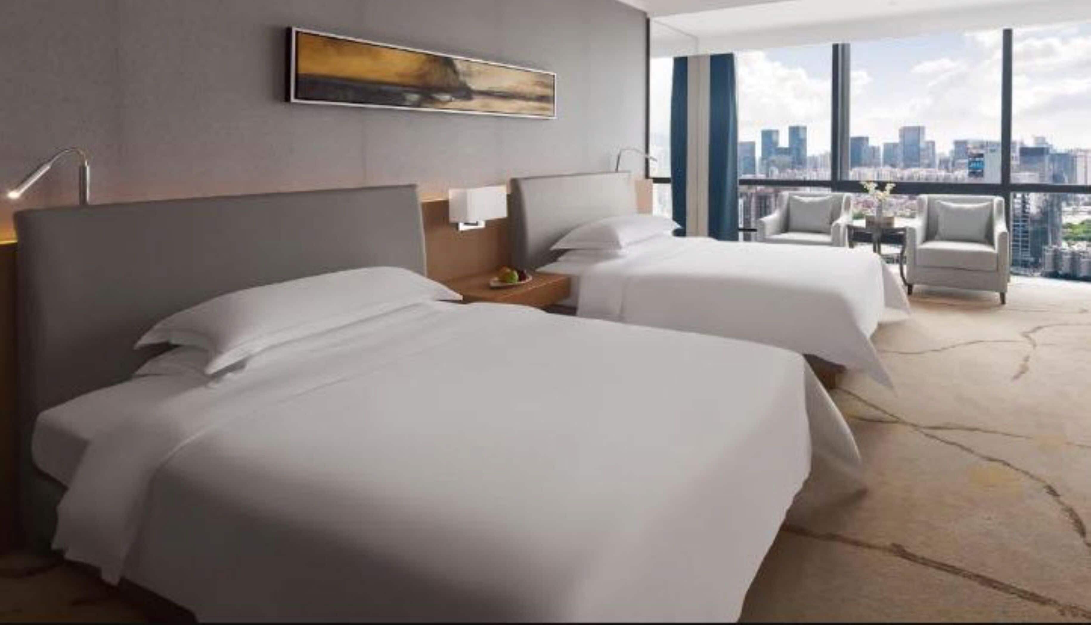 A hotel room with two beds, a city view, and a modern design.