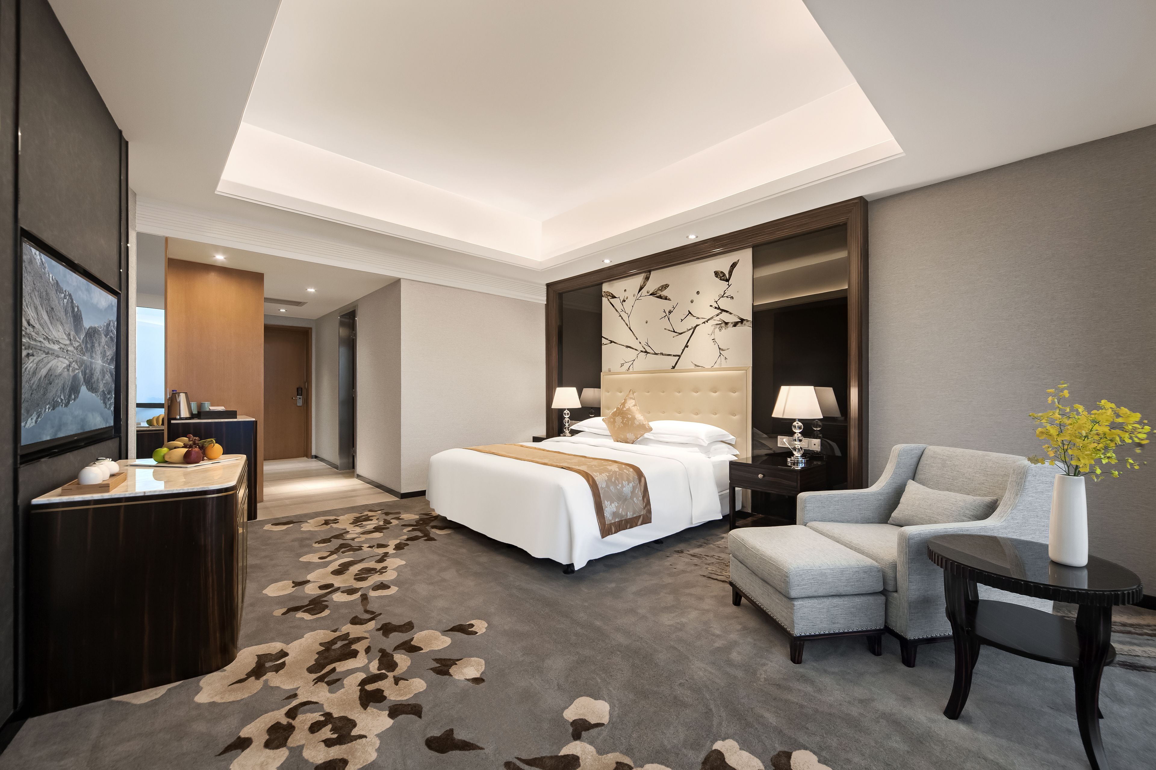 Ein modernes Hotelzimmer mit einem großen Bett, einer Sitzecke, einem Schreibtisch und einer Wanddekoration.