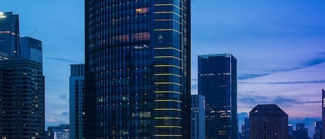 Un hotel de gran altura con fachada de vidrio moderna, rodeado de otros edificios en un paisaje urbano.