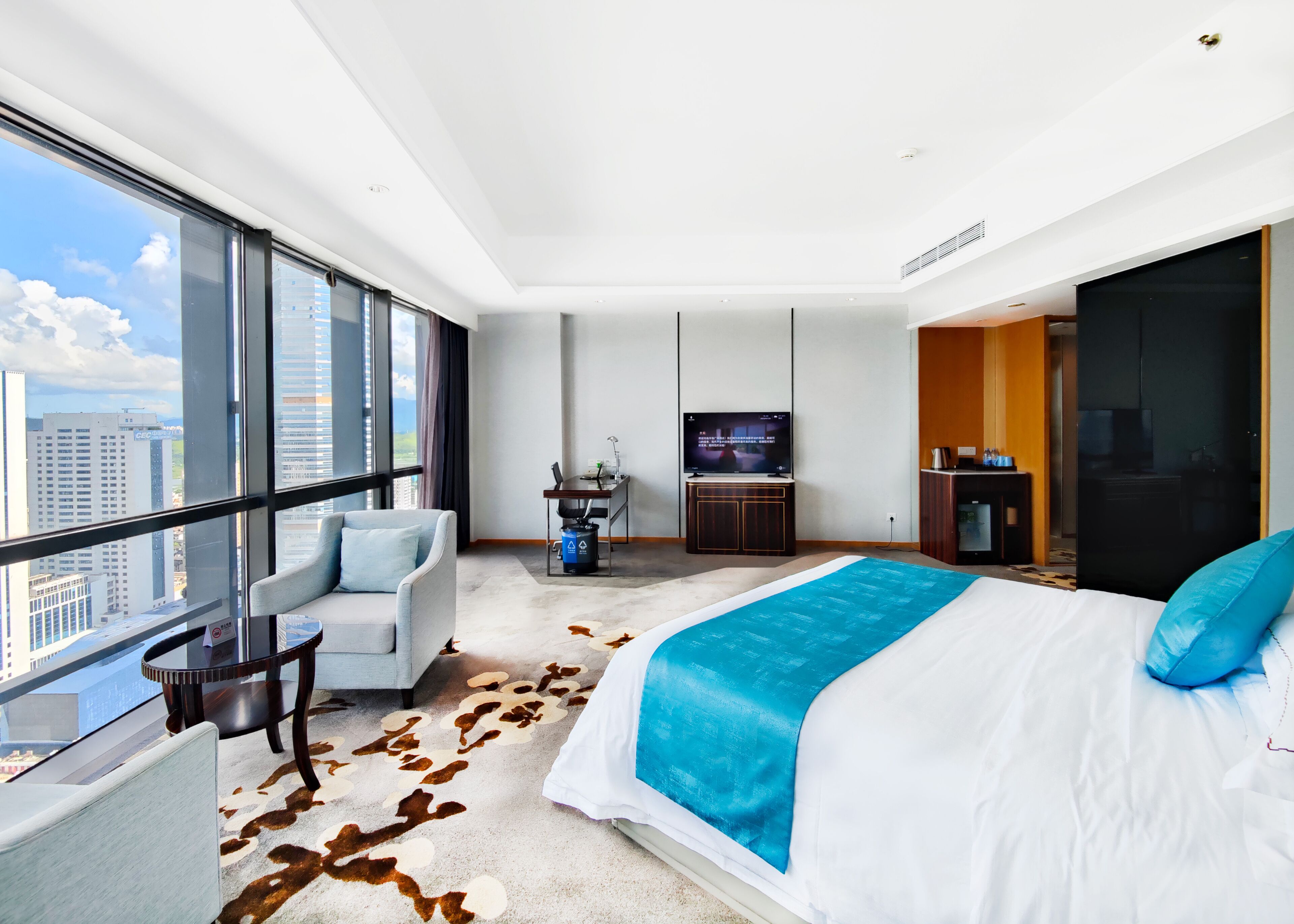 Habitación de hotel moderna con una cama grande, televisión, escritorio y vistas a la ciudad.
