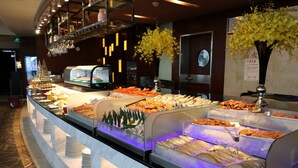 Un bufé con diversos alimentos y un jarrón decorativo con flores amarillas.