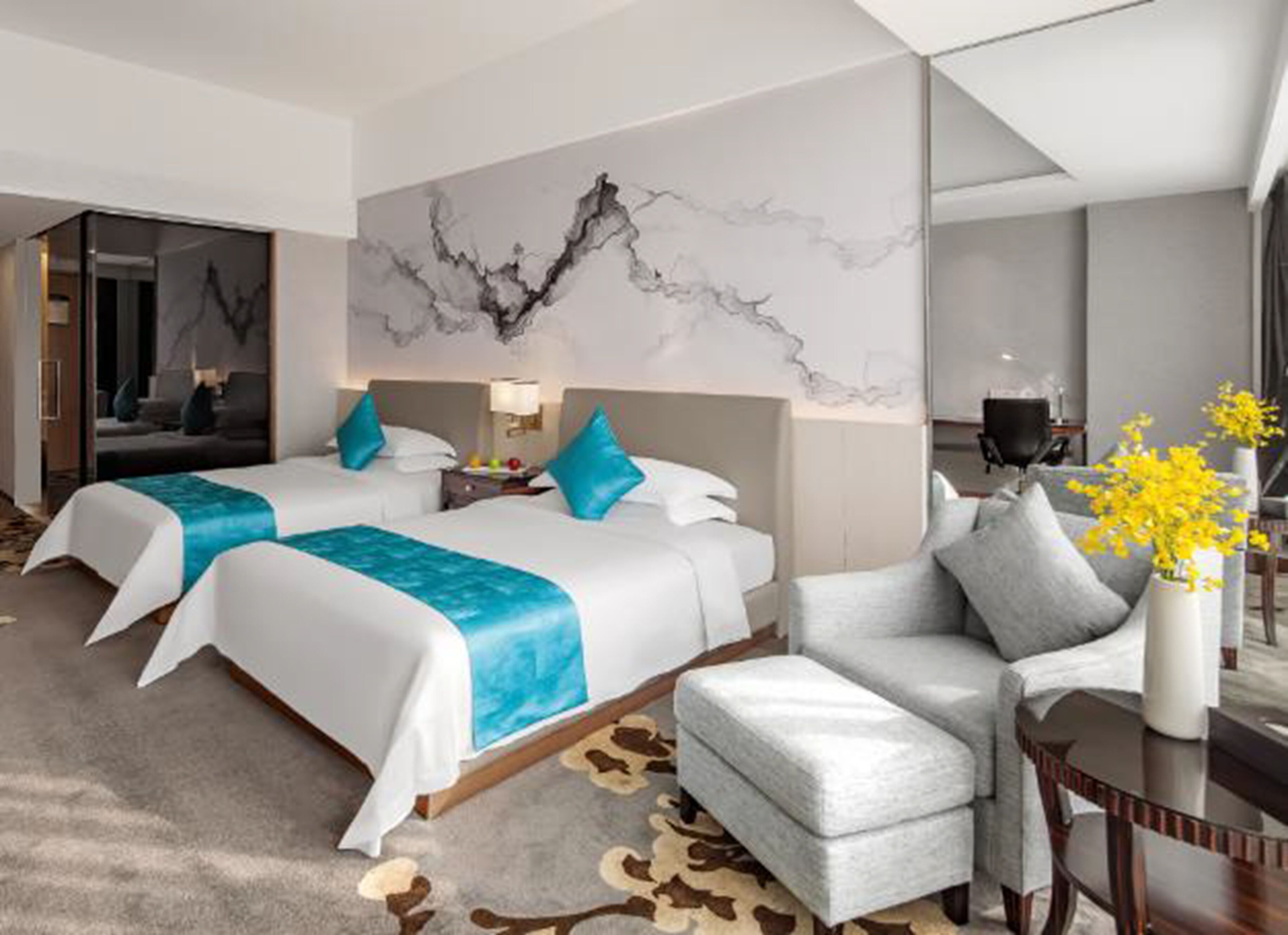 A hotel room with two beds, a sofa, a desk, and a large abstract painting on the wall.
