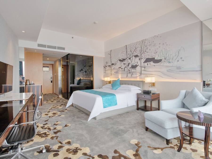 Una habitación de hotel con cama, escritorio, silla, sofá y una pequeña mesa.