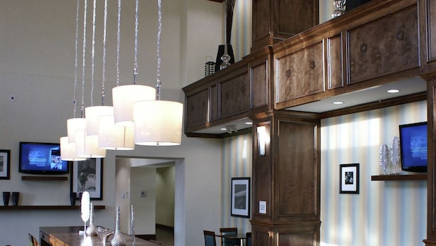 A spacious dining area with a long wooden table, multiple chairs, hanging pendant lights, and a television on the wall. - Hampton Inn & Suites Center (Center)