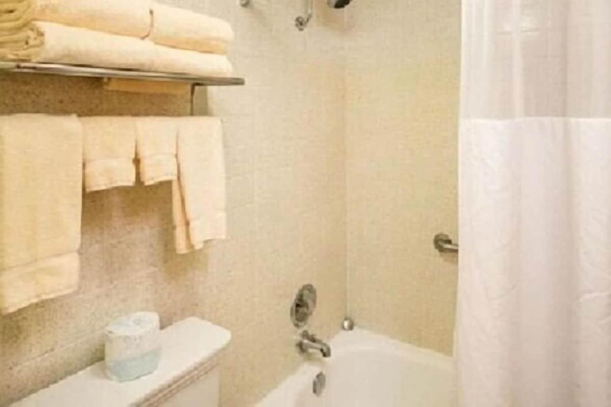 A bathroom with a toilet, a sink, a bathtub, and a towel rack with folded towels.