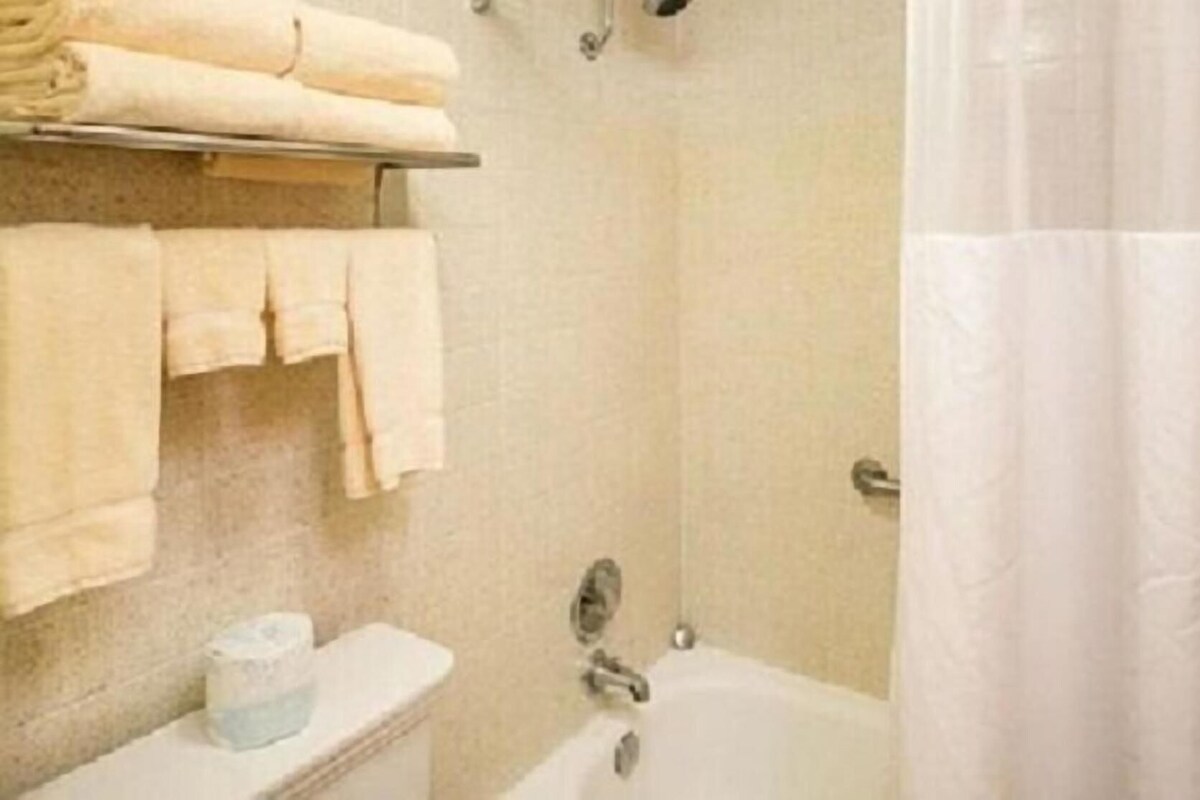 A bathroom with a toilet, a sink, a bathtub, and a towel rack with folded towels.
