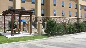 A multi-story hotel with a stone facade, a covered outdoor seating area, and a paved entrance.
