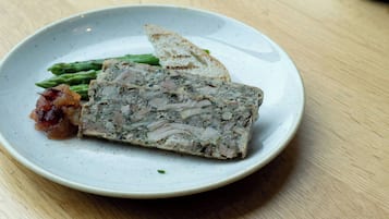 Un plato con un guiso de carne, espárragos y una rebanada de pan sobre una mesa.