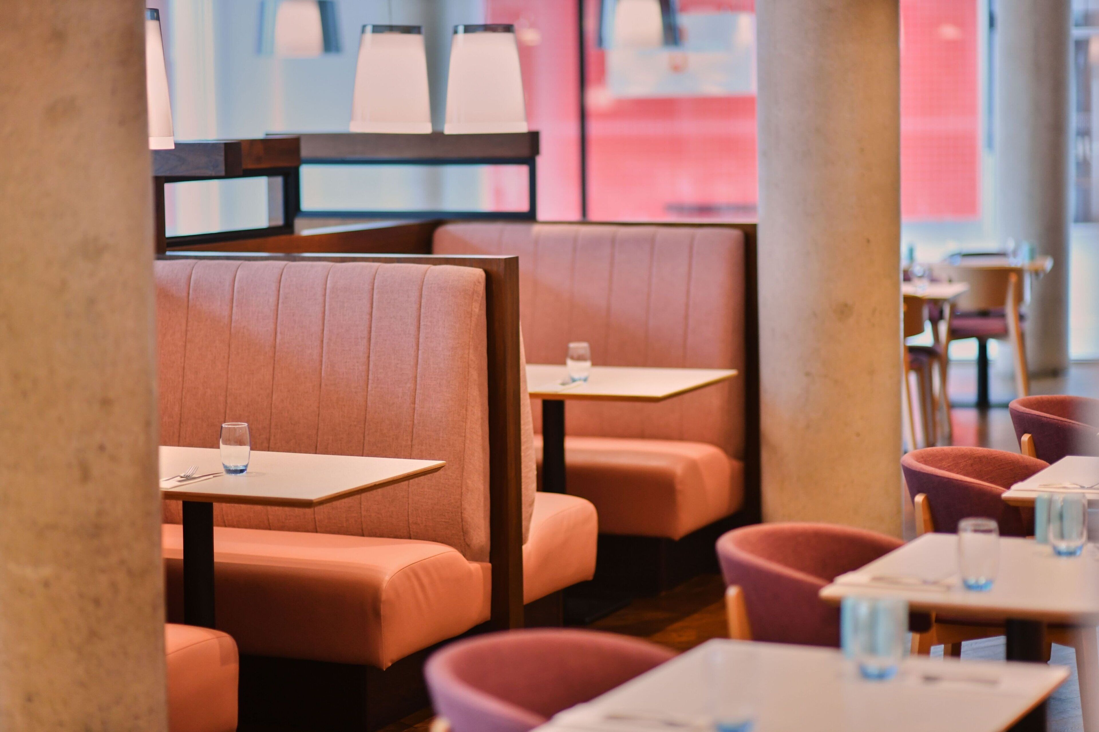 Un interior de restaurante con cabinas y mesas, algunas con vasos de agua.
